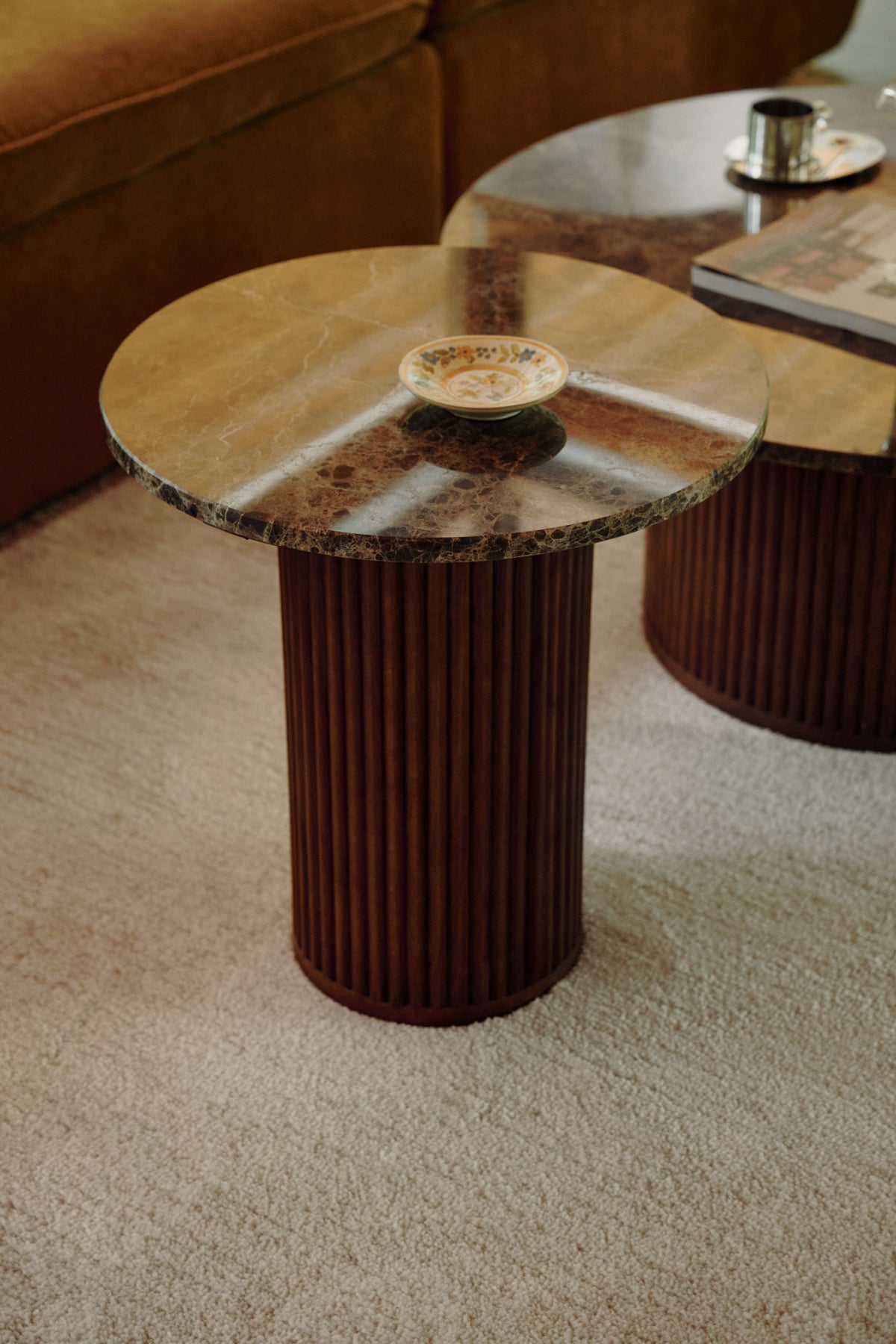 table d'appoint Oviedo en marbre Emperador et socle cannelé devant un canapé ocre